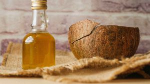 bottle of coconut oil next to a coconut