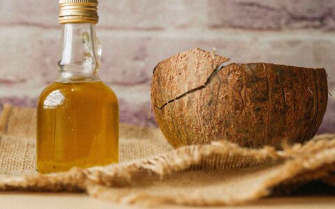 bottle of coconut oil next to a coconut