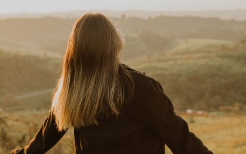 Woman enjoying fresh air outdoors while practicing nasal breathing in a peaceful natural setting.