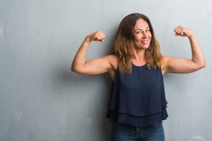 A woman smiles and flexes her biceps.