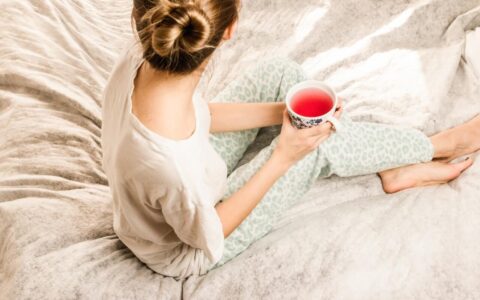 woman sitting on bed with tea