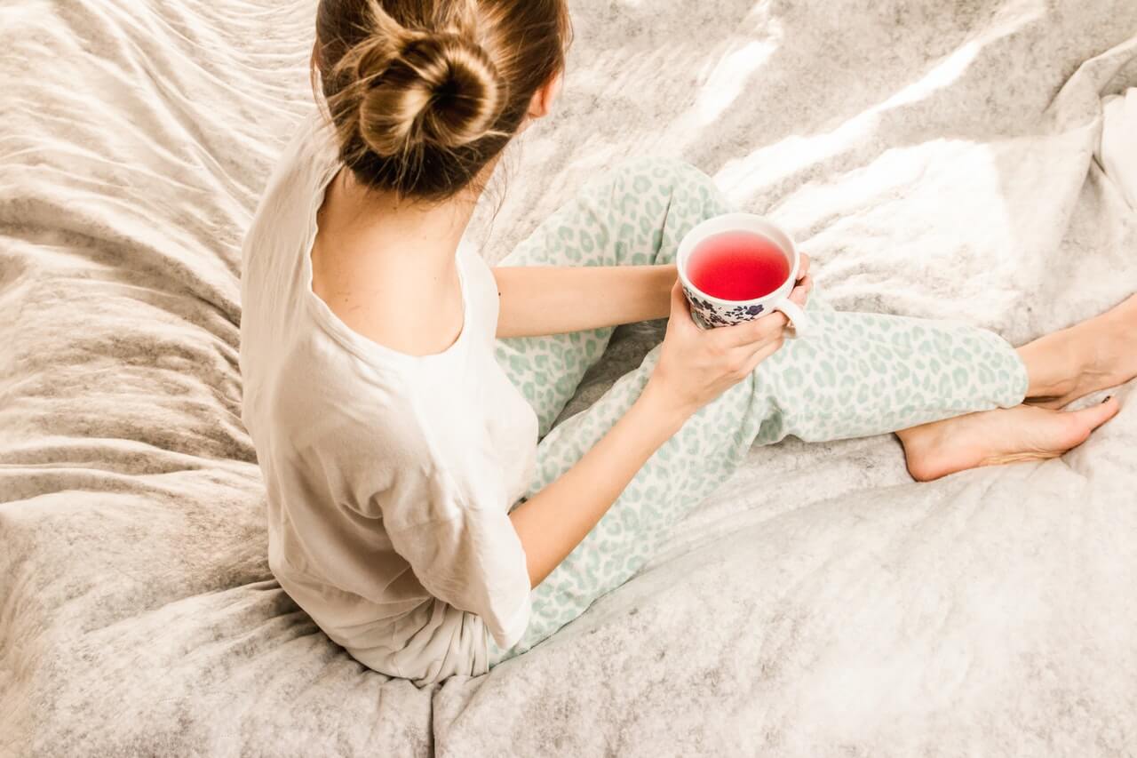 woman sitting on bed with tea