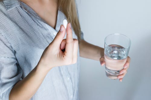 Woman holding pill and water