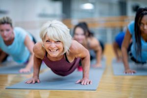 Senior Woman in Fitness Class in a Plank Pose Smiling