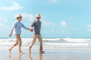 A couple walks on the beach, with waves crashing behind them.