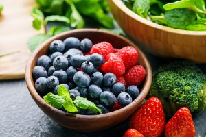 A bowl sitting on top of a table is full of blueberries and raspberries.
