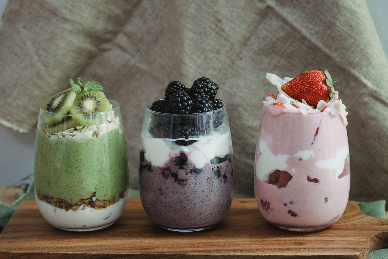3 cups filled with yogurt and a variety of fruits