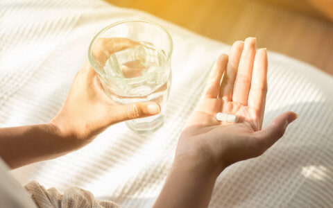 Glass of water with supplement in hand