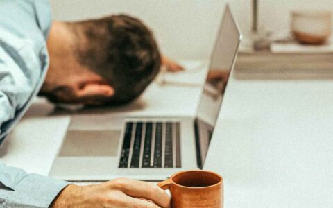 man sleeping next to his laptop
