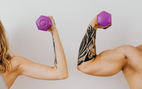 two people flexing holding dumbells