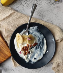 bowl of yogurt with sliced banana bites and almonds