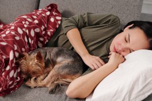 woman laying on couch with dog