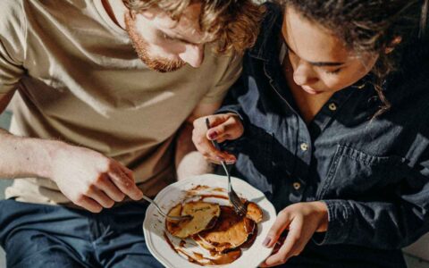 two people sharing food off a plate