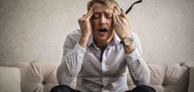 man appearing stressed holding his eye glasses