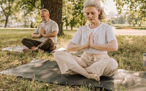 two seniors meditating outside