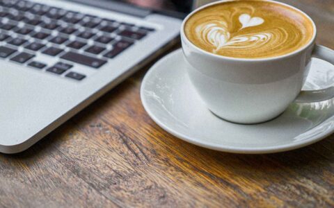 cup of coffee next to a laptop