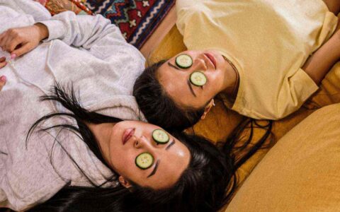 two woman with cucumber slices over their eyes