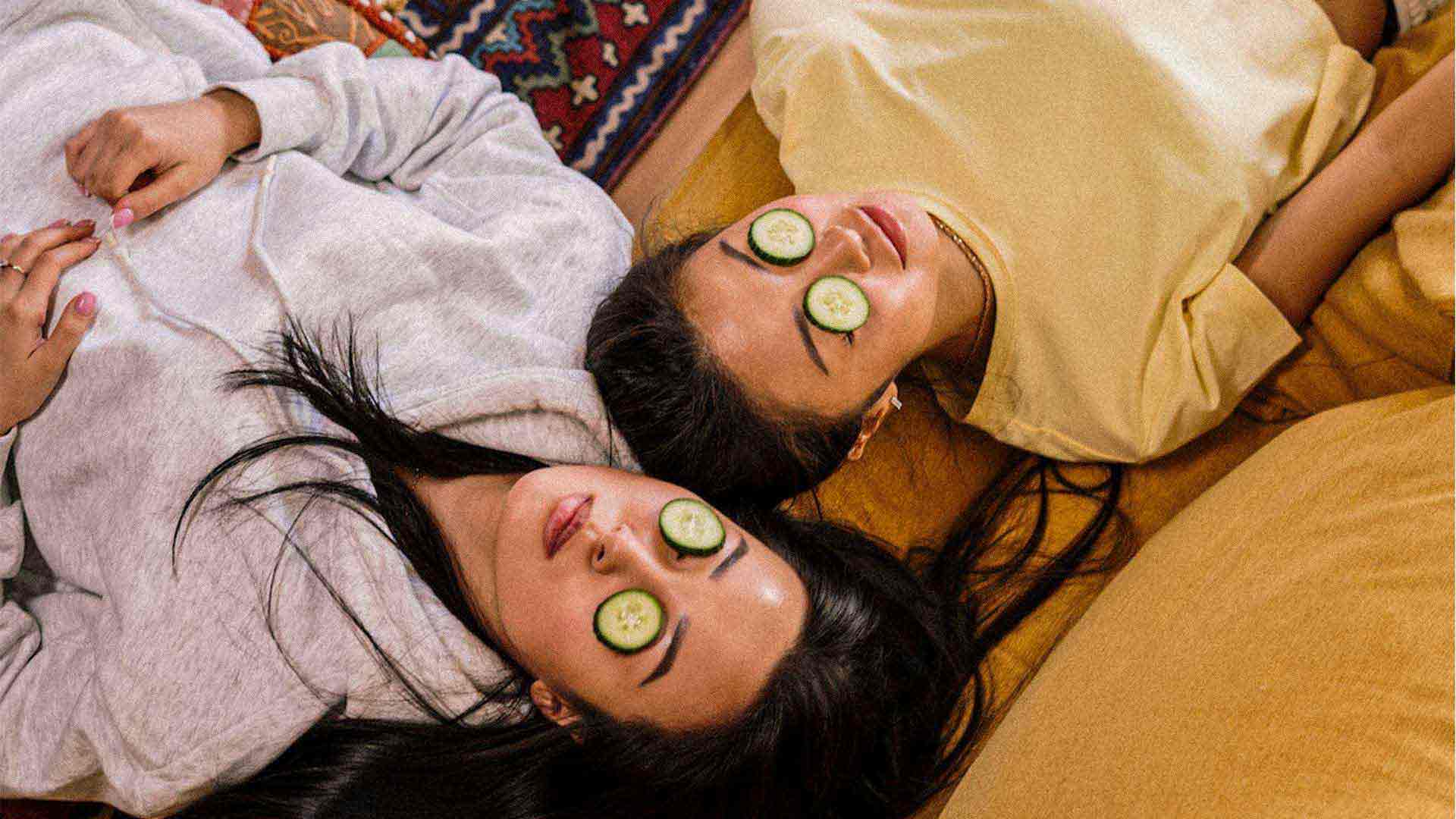 two woman with cucumber slices over their eyes