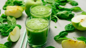 two glass cups filled with a green smoothie