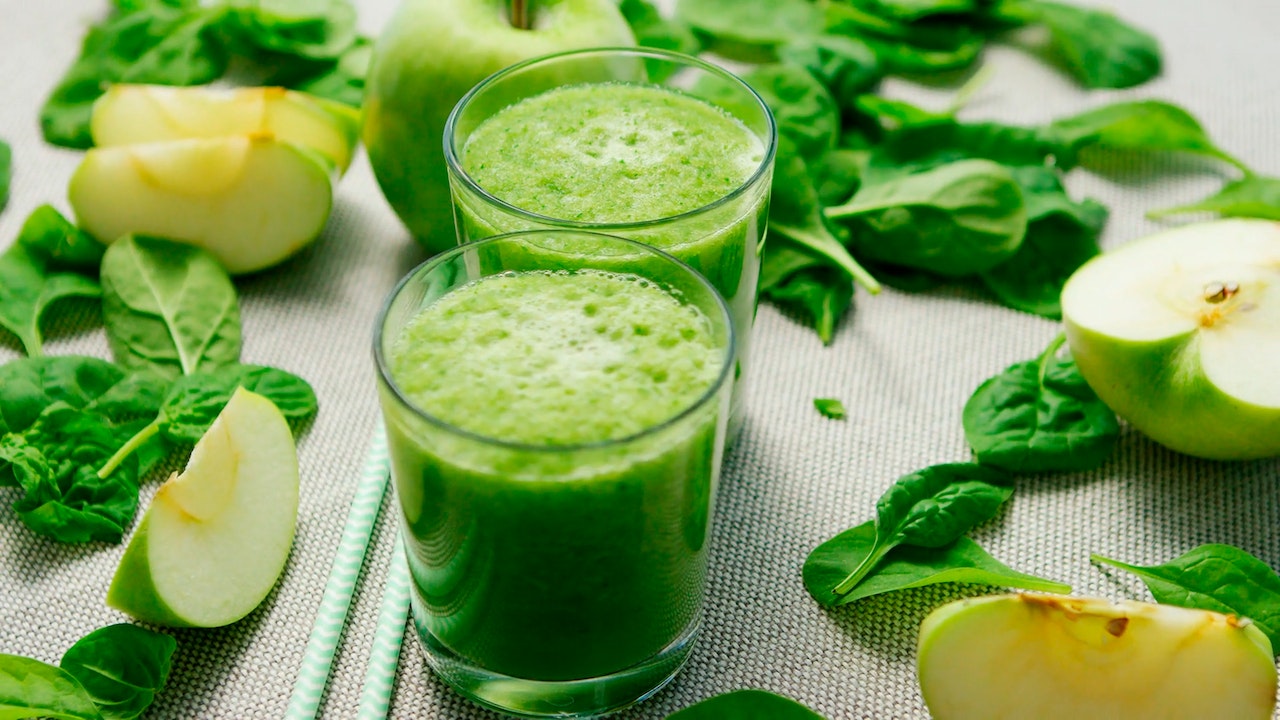 two glass cups filled with a green smoothie