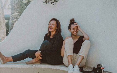 two women sitting outside laughing