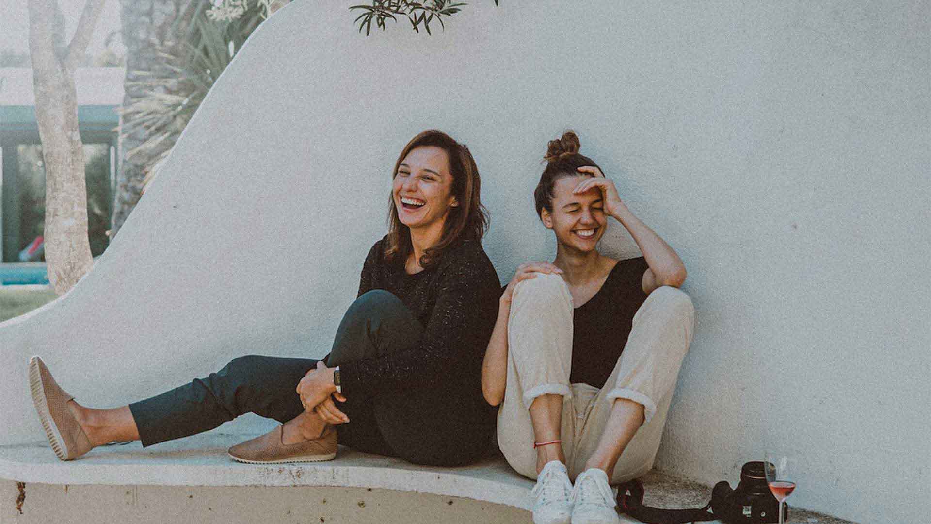 two women sitting outside laughing