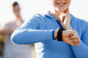 Young runner woman with heart rate monitor running on beach