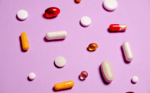 Assorted red white and yellow medication and vitamin pills on white surface representing daily multivitamin supplements